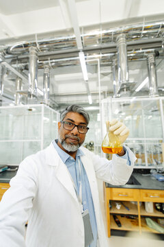 Male scientist holding vaccine vial in laboratory, UGC style.