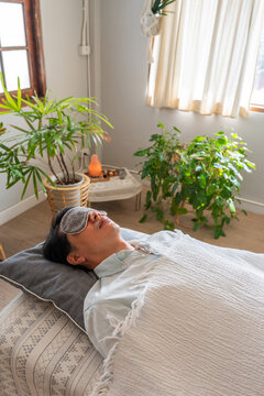 Man Resting in a Bright Room With Plants and Soft Bedding