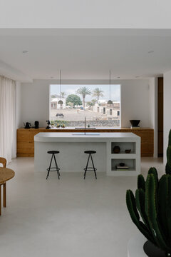 Modern kitchen framed by large window inside minimalist designer home
