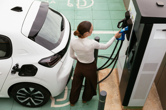 Woman charging electric car at public station