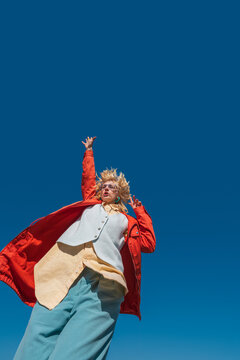 Low angle view of dancing woman with raised arm and flowing coat