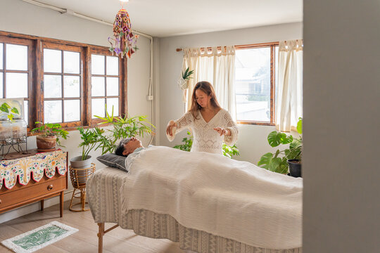 Woman Performs Healing Session in Bright Room With Plants