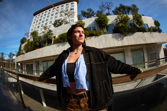 Person stands with arms outstretched in urban setting under blue
