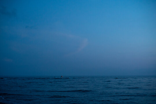 Small boat on open sea under blue evening sky