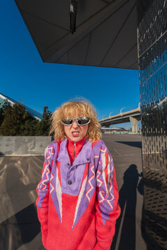 Woman in colorful sweater standing near modern urban architecture