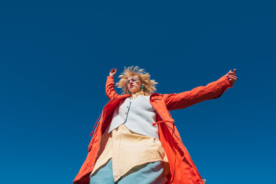 Stylish person using smartphone outdoors under clear blue sky