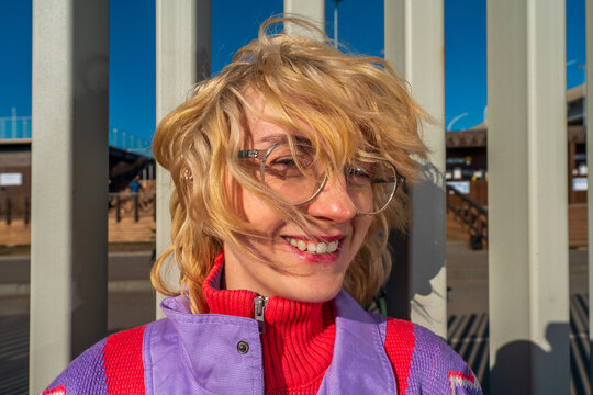 Smiling woman with windblown hair by vertical columns