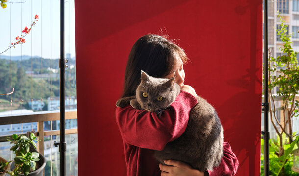 A Chinese girl holding a cat on a balcony during Chinese New Year