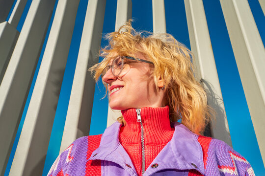 Smiling woman in colorful sweater by vertical architectural columns
