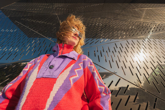 Low angle woman in colorful sweater and sunglasses outdoors