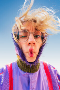 Playful woman making funny face with windblown hair outdoors