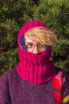 Woman in bright knitted balaclava and glasses outdoors portrait