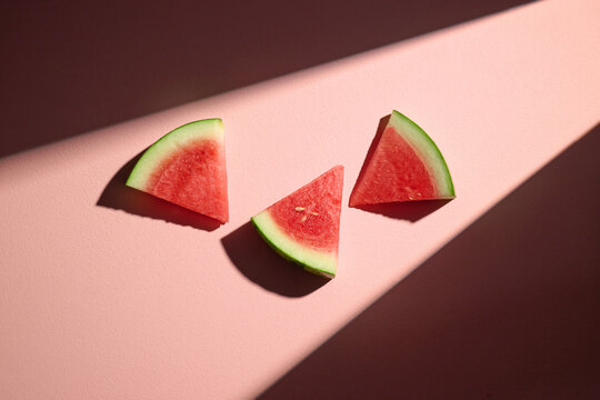 Watermelon slices on a pink background with interesting light
