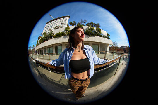 Woman stands outdoors with arms open in city setting