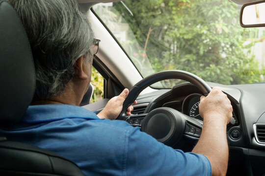 asian elderly man driving happily in the car