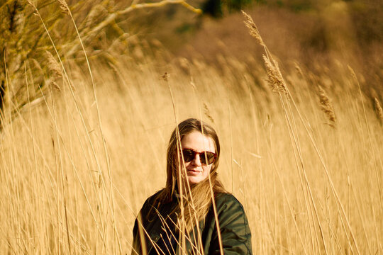 Blonde woman with sunglasses among dry bushes in spring
