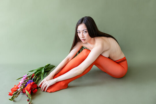 A woman poses with flowers in a studio setting