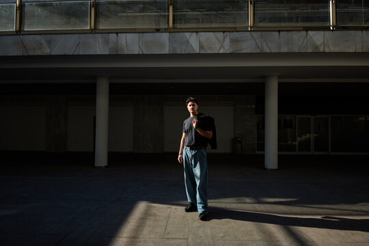 Person stands in shadows near a building in a city