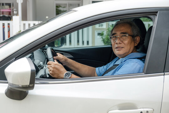 Handsome older man is driving his car and looking trough the window