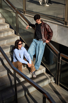 Couple sitting on stairs in urban location during sunny day