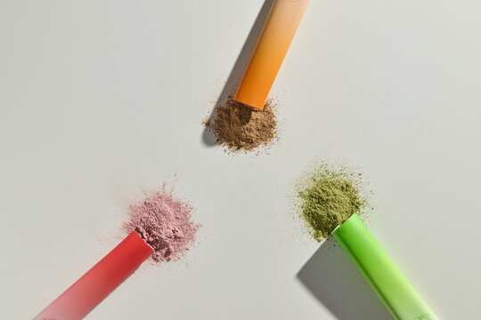 Three colorful supplement powders spilling from tubes