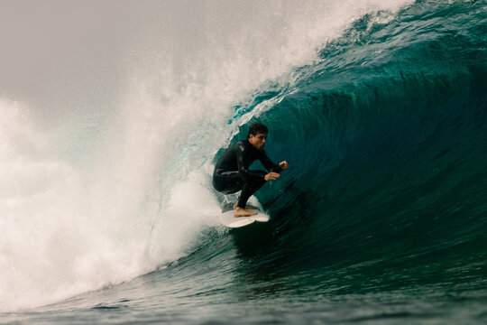 Surfer carving deep inside the hollow tube of a towering wave