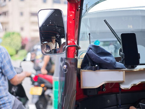 Refection of tourist in Tuk-Tuk mirror in busy Colombo traffic scene