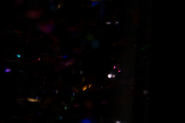 Abstract background of colorful bokeh lights and iridescent glimmers on dark with blurred motion...