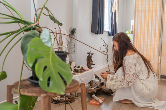 Woman Arranging Objects on a Table in a Bright Room