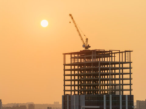 Under Construction Skyscraper with Tower Crane at Golden Sunset