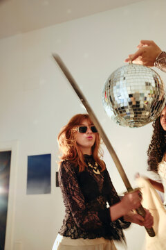 Woman holding katana sword indoors during party