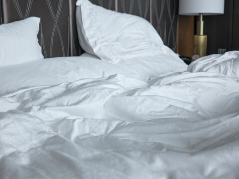 Comfortable Bed With White Linen Sheet in Unmade state