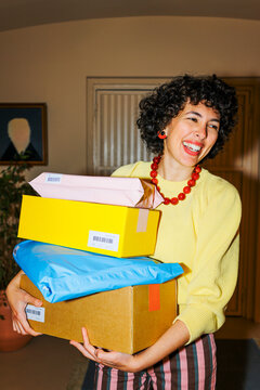 Woman carrying a stack of parcels at home ugc