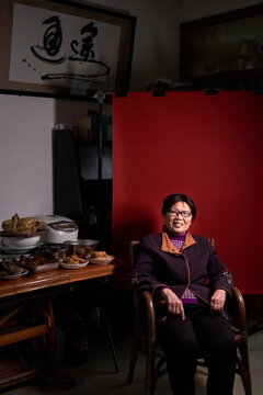 An elderly Chinese woman at home with a red background