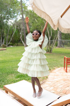 Child in a Bright Dress Enjoys Sunny Day Outside