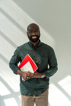 Portrait of Smiling Man Holding Notebooks in Casual Shirt 