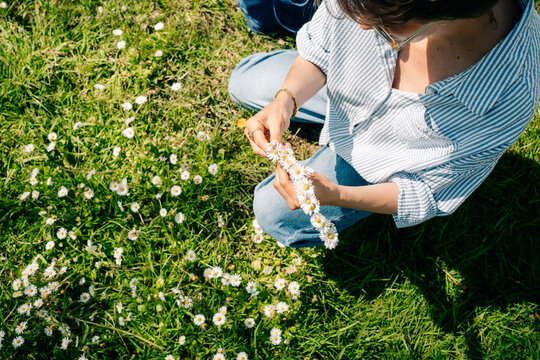 Woman Making a Flower Crown in a Grassy Field During the Day