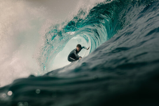 A professional surfer ride deep inside the hollow barrel of a wave