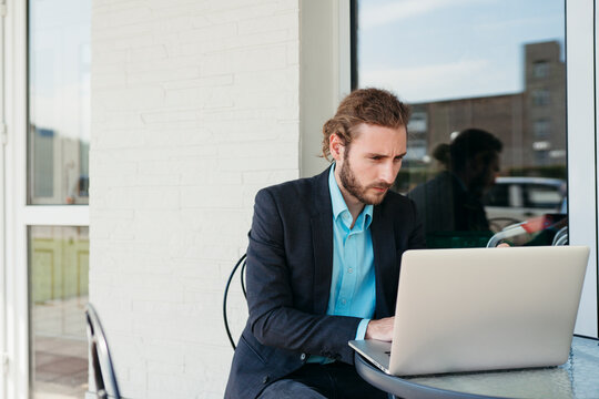 Focused Professional Working on a Laptop at a Sunny Cafe Terrace