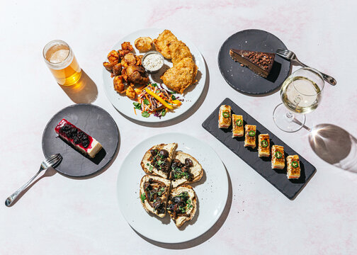 Plates of sushi, dessert, fish and chips, mushroom toast and drinks