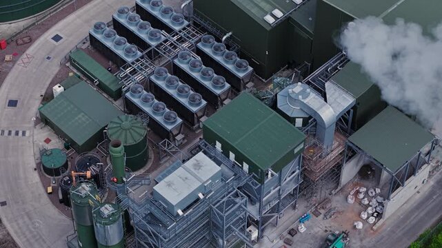 Aerial view of Biogen Atherstone anaerobic digestion plant with cooling units, industrial buildings and steam rising from a chimney in Atherstone, England, United Kingdom.