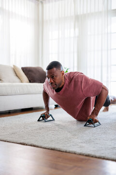 Man doing push-ups with handles in living room.