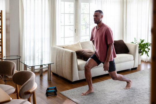 Man doing lunges in a bright living room.