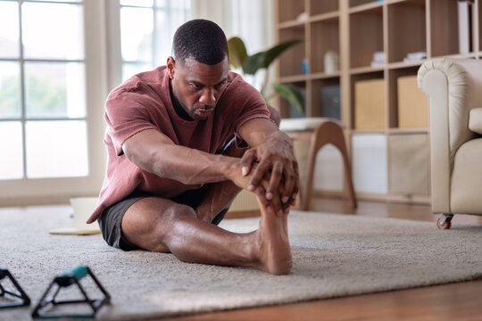 Man stretching leg on floor in living room.