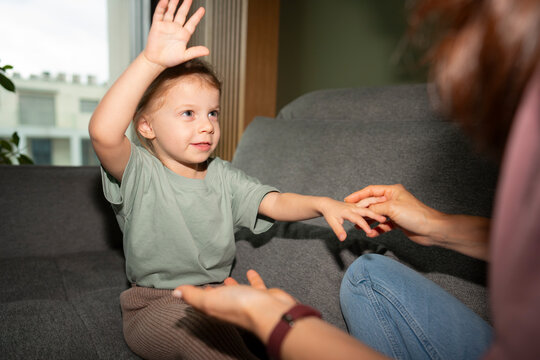 Child raises hand while sitting on a couch