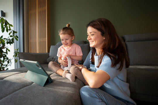 Mother and daughter share time watching a screen