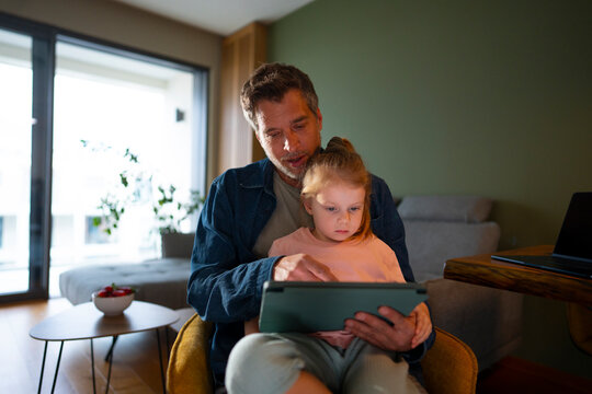 Dad and daughter learning on tablet together