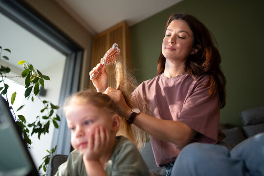 Mom brushes daughter's hair at home