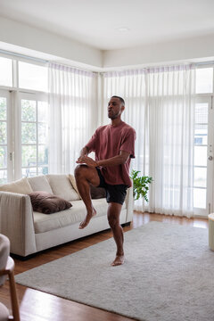 Active man performing high knee exercise in a modern living room