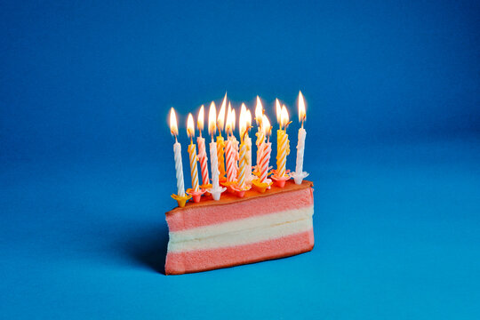 a crowded cluster of lit candles on a pink and white layered cake